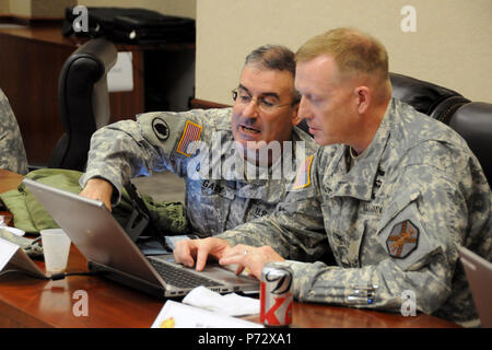 Lt. Col. Patrick Gary (sinistra), staff giudicare l'avvocato, consulta Col. Stuart McRae, Fort Rucker, Ala. garrison commander, durante l'installazione del primo virtual town hall meeting al post della sede Giugno 4, 2013. L'ora di incontro virtuale, che è stato presentato su Facebook, ha offerto la possibilità di Fort Rucker leader di rispondere alle domande dei residenti e lavoratori della base. Foto Stock