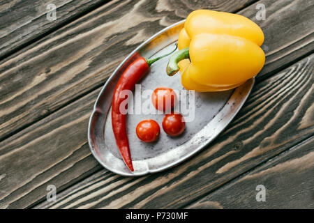 Peperoni e pomodori ciliegia in argento vassoio sul tavolo di legno Foto Stock