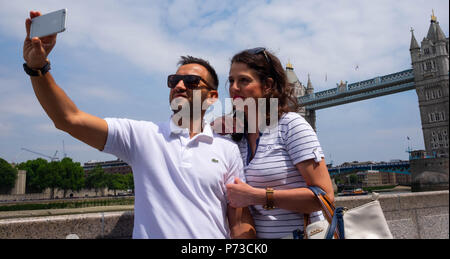 Londra, Inghilterra. 4 luglio 2018. La Georgia e il suo fidanzato, turisti provenienti dalla Grecia, prendere un selfie vicino al Tower Bridge su un'altra giornata molto calda. La presente ondata di caldo è impostata per continuare. ©Tim anello/Alamy Live News Foto Stock