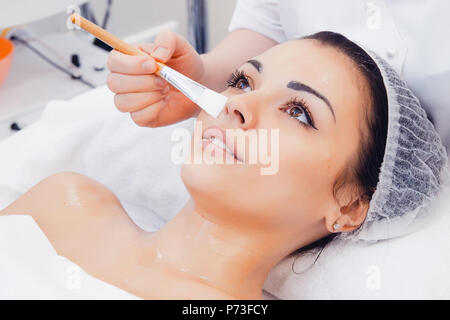 La pelle del viso cura. Estetista applicare olio di bellezza maschera sul viso utilizzando la spazzola in Spa Salone. Vista dettagliata del Client femmina Getting idratare la procedura in bellezza C Foto Stock