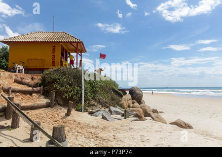 Florianopolis, Santa Catarina, Brasile. Bagnino riposare sulla spiaggia con bandiera rossa, indicando un pericoloso mare sulla soleggiata giornata estiva. Foto Stock