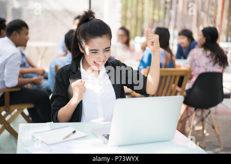 Business di successo di donna con le braccia in alto,Asian Business donna con abito casual lavora con azione di felice in ufficio o negozio di caffè. Foto Stock