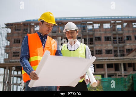Costruzione Engineers discussione con gli architetti in cantiere o sito di costruzione di edificio highrise Foto Stock