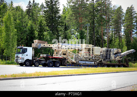 100 000 kg trasporti pesanti di Metso Lokotrack crusher da Sisu E18 semi rimorchio di Telamurska Oy in movimento in estate. Salo, Finlandia - 30 giugno 2018. Foto Stock