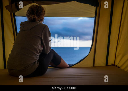 Lonely forte indipendente di mezza età sentimento donna la natura outdoor in una tenda del tetto sulla vettura. viaggi e lifestyle wanderlust concept per il bellissimo Foto Stock