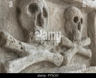 Antico casale in pietra con cranio crossbones. Scultura antica. Ideale per i concetti e gli sfondi. Foto Stock