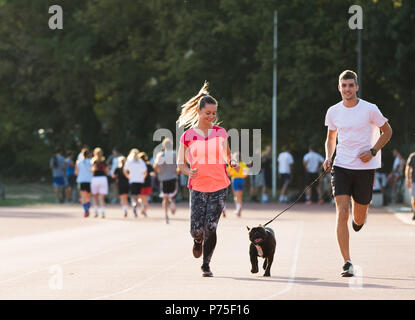 Coppia giovane acceso con bulldog francese al campo sportivo Foto Stock