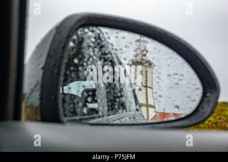 Faro e pioggia attraverso auto specchio retrovisore Foto Stock