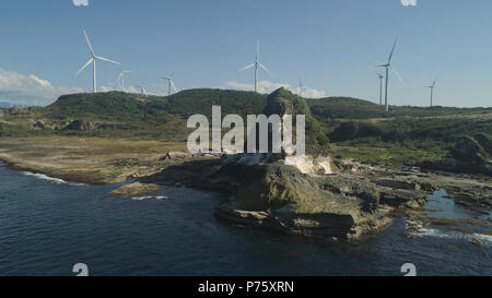 Formazione rocciosa naturale di pietra calcare sulla costa con mulini a vento per la produzione di energia elettrica. Vista aerea di attrazione turistica Kapurpurawan Rock Formazione in Ilocos Norte Filippine,Luzon. Foto Stock