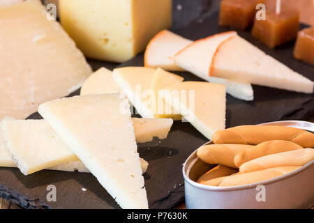 Tabella di formaggi assortiti con pane su piastra in ardesia Foto Stock