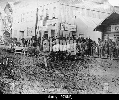 . Inglese: Cavallo carrello trasporto legname bloccato nel fango sulla parte anteriore San, Dawson, Yukon Territory, ca. 1899. Inglese: Mostra "Il dominio' e 'Arcade Restaurant' nella didascalia di sfondo sull'immagine: '(Front Street) Dawson Main Street 1898' fotografia originale da Eric A. Hegg 3094; copiato da Larss e Duclos . No. 33 appare nell'angolo inferiore sinistro. Klondike Gold Rush. Soggetti (LCTGM): Ristoranti--Yukon--Dawson; quartieri degli affari--Yukon--Dawson; progetto di animali--Yukon--Dawson; fango--Yukon--Dawson; carrelli e carri--Yukon--Dawson; legname--Yukon--Dawson soggetti (LCSH): Front Street (Dawson, Yukon); Arcade ri Foto Stock