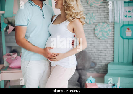 Pragnancy giovane famiglia si erge tra i giocattoli. Foto Stock