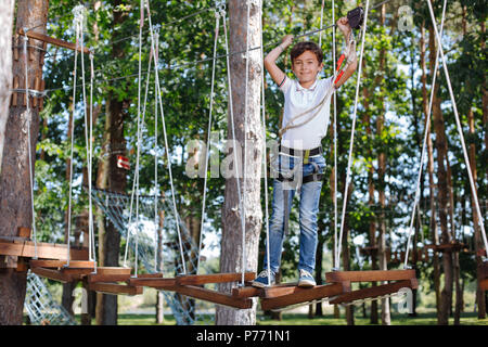 Upbeat preteen boy in posa a fune park Foto Stock