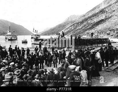 . Inglese: guida l'ultimo spike del White Pass & Yukon Ferrovia a Lago di Bennett, British Columbia, Luglio 6, 1899. Inglese: mostra due piroscafi in background e la folla osservando la cerimonia . Didascalia sulla immagine: "l'influenza l'ultimo spike del Pass bianco e Yukon RR a Lake Bennett. 6 luglio '99'' Klondike Gold Rush. Soggetti (LCTGM): laghi e stagni--British Columbia; Railroad Costruzione & Manutenzione--British Columbia--Bennett; i binari della ferrovia--British Columbia--Bennett; piroscafi--British Columbia--Bennett soggetti (LCSH): Bennett, Lago (a.C.); White Pass & Yukon Route (Azienda) . 189 Foto Stock