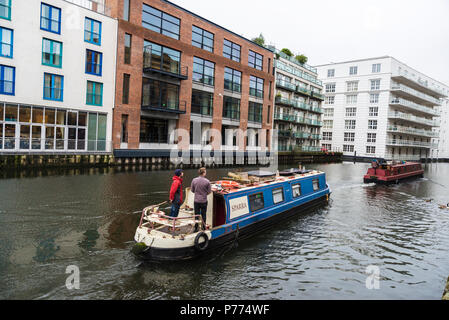 London, England Regno Unito - Dicembre 31, 2017: navi per la navigazione al Regent's Canal guidato da un uomo al timone vicino al mercato di Camden con la moderna sede, Foto Stock