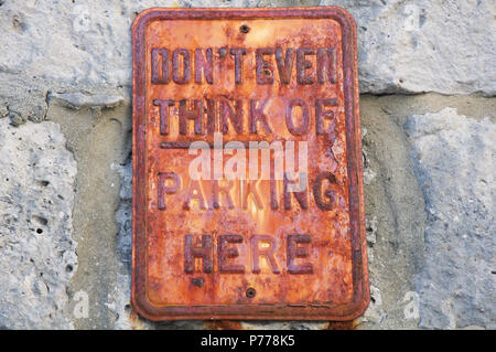 "Non pensate nemmeno di parcheggio qui". Divertente nessun messaggio di parcheggio su un arrugginito textured vecchio Cartello in metallo. Isola di Portland, Dorset, Inghilterra, Regno Unito. Foto Stock