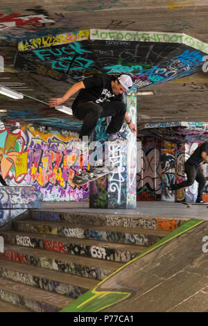 Londra Southbank Skatepark graffiti guidatore di skateboard in volo giù per le scale passi lo skateboard jump trucco azione acrobatica di specialità Foto Stock