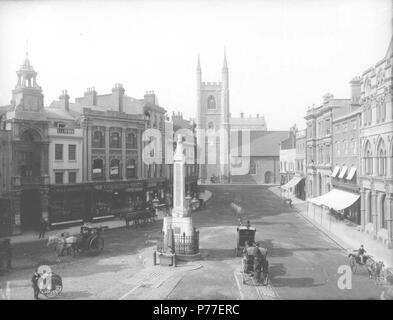 Inglese: Market Place, leggendo, guardando verso nord per San Lorenzo è la Chiesa, c. 1875. Sul lato ovest, l'ingresso per il Corn Exchange con orologio sopra; n. 34 e 33 (salmone e figlio, bollitore per tè e caffè commercianti); n. 32; n. 31 e 30; n. 29 (Arthur S. Cooper, vino e lo spirito merchant). Sul lato est, n. 19 e 18 (l'Elefante Hotel); n. 17 (Frank Cooksey, agente immobiliare); n. 16, 15, 14 e 13 (a Londra e nella contea di banca); n. 12 (Morris e Davis, sarti); n. 11 e 9 (Sutton e figli, seedsmen); e n. 7 ("Lettura Mercury' uffici). Due cabine attendere da Simeone obelisco, che ha un pum Foto Stock