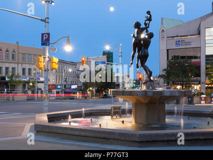'Famiglia' la scultura e la fontana di San George Square al tramonto nel centro cittadino di Guelfo, Ontario, Canada. Foto Stock