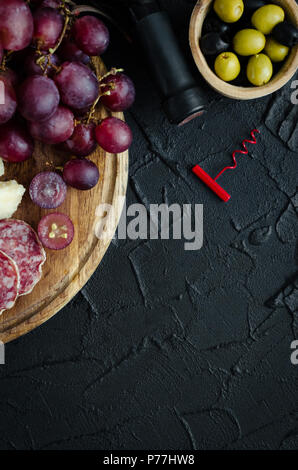 Bottiglia di vino, cavatappi e antipasti. Un assortimento di stile Italiano cibo banchetti set. Deliziosi snack sulla parte. Tagliere con salame, uva e par Foto Stock
