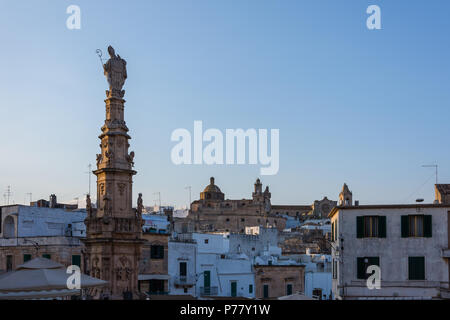 Ostuni, Italia - 11 agosto 2017. Obelisco Sant'Oronzo obelisco nella piazza principale di Ostuni con Basilica Minore Concattedrale di Santa Maria Assunta cathe Foto Stock