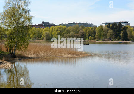 HELSINKI, Finlandia - 13 Maggio 2018: persone fila una barca sul Toolo bay nel parco della città di Helsinki. Scandic Park e gli alberghi Crowne Plaza Hotels può essere visto in precedenza Foto Stock