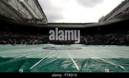 Il personale di terra mettere le copertine sul Centre Court come la pioggia smette di giocare il giorno tre i campionati di Wimbledon al All England Lawn Tennis e Croquet Club, Wimbledon. Foto Stock