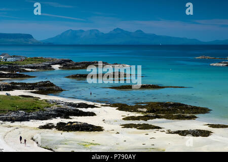 Persone su una spiaggia sabbiosa di Traigh vicino Arisaig con le isole di Eigg e rum in distanza. Foto Stock