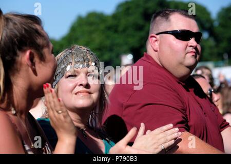 Donna in festival folla indossando stile cleopatra argento testata battendo le mani e sorridente Foto Stock