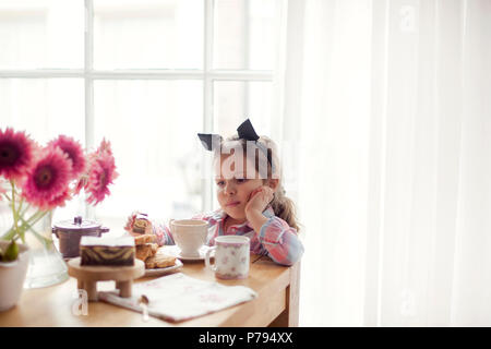 Una bambina a tavola è mangiare la prima colazione presso la finestra. Buona mattina. Spazio di copia Foto Stock