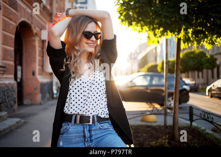 Ritratto di donna sorridente in serata. Felice giovane ragazza camminare intorno alla città, ritratto sullo sfondo della città. Foto Stock