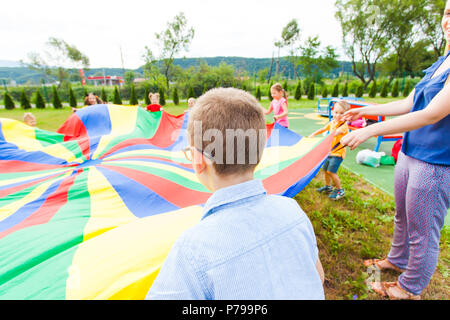 La vista posteriore di un ragazzo con paracadute di grandi dimensioni nelle sue mani Foto Stock