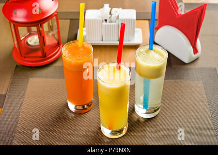 Tre di vetro con una mela, arancio e carota succo di frutta fresco, sul tavolo nel ristorante Foto Stock
