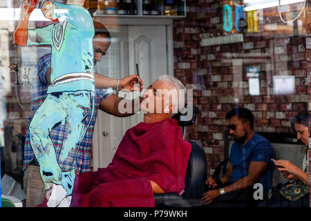 Un uomo avente una rasatura bagnata in un salone di parrucchiere, Brick Lane, London, Regno Unito Foto Stock