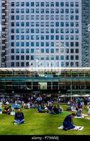 Gli impiegati seduti sul prato del pranzo, Canary Wharf, London, Regno Unito Foto Stock