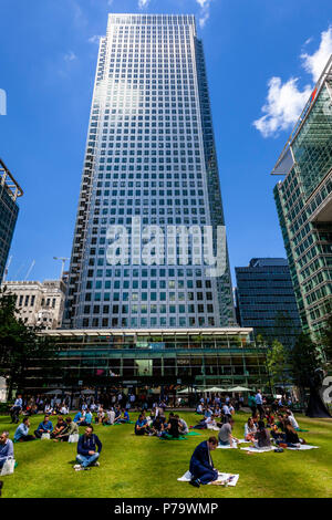 Gli impiegati seduti sul prato del pranzo, Canary Wharf, London, Regno Unito Foto Stock