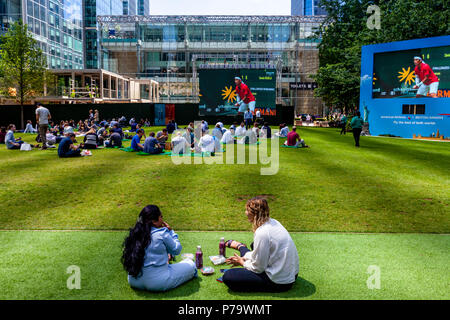 Gli impiegati seduti sul prato del pranzo, Canary Wharf, London, Regno Unito Foto Stock