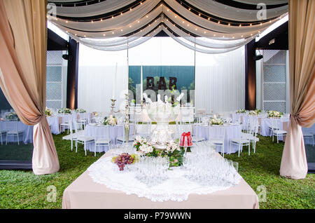 Un ampio angolo di visione di un ricevimento di matrimonio venue, con pista da ballo e tabelle circostante. Un grande lampadario nel mezzo della camera dispone di attrezzatura drappeggiati con mini luci. Foto Stock