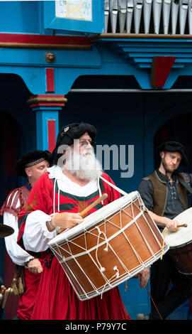 Il batterista e il gruppo che esegue con tamburi a la Festa del Rinascimento, Maryland. Il grande tamburo appeso al collo del reenactor medievale in costume rosso. Foto Stock