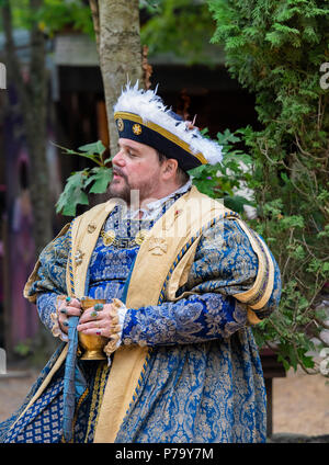 Maryland Renaissance festival attore raffigurante il re Enrico VIII in appoggio all'aperto, con un drink nel suo bejeweled mani. Egli sta cercando la distanza. Foto Stock