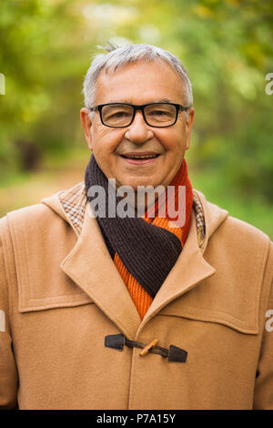 Outdoor ritratto di felice senior uomo che indossa rivestire in autunno. Foto Stock