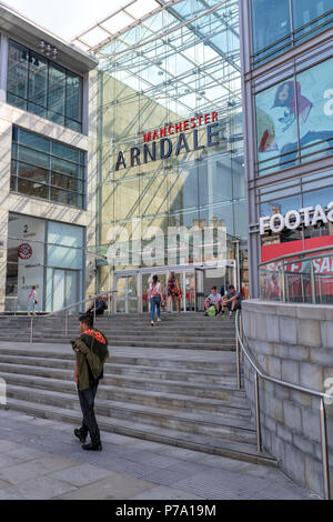 Un giovane uomo cammina passato l'ingresso al Manchester Arndale Centre. Manchester, Regno Unito Foto Stock