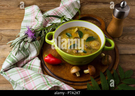 Fungo zuppa fatta in casa nel verde della piastra rustico e pepe mulino sul tavolo di legno. Vegetariano cibo sano Foto Stock