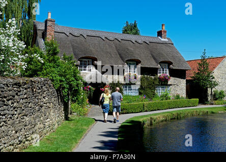 Cottage con il tetto di paglia & Thornton Beck, Thornton-le-Dale, North Yorkshire, Inghilterra, Regno Unito Foto Stock