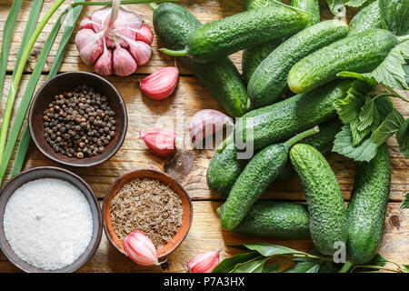 Ingredienti per la conservazione su un vecchio tavolo di legno-cetrioli, aglio, aneto semi, pepe, sale, condimenti e spezie . Messa a fuoco selettiva Foto Stock