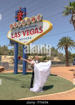 Sposa e sposo a Benvenuto al Favoloso segno di Las Vegas. Sposi sposi in posa per la foto, lo sposo alzando la sposa con bouquet nelle sue braccia. Foto Stock