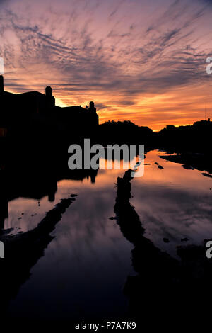Tramonto colorato con riflessi del cielo in una pozzanghera dopo un giorno di pioggia Foto Stock