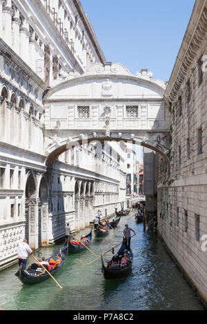 Gondole con i turisti in barca a remi sotto il Ponte dei Sospiri (Ponte dei Sospiri) , San Marco, Venezia, Veneto, Italia tra il Palazzo dei Dogi e veneziano Foto Stock