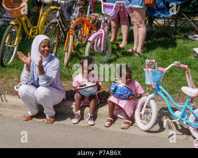 Oak Park, Illinois, Stati Uniti d'America 4 Luglio, 2018. Una donna musulmana con identiche due gemelle gode il Giorno di Indipendenza sfilata in questo sobborgo appena a ovest di Chicago. Temperature di questo 4 di luglio erano ben al di sopra di 90ºF/32ºC con un indice di calore di oltre 100ºF. Credito: Todd Bannor/Alamy Live News Foto Stock