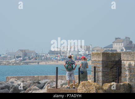 Lyme Regis, Dorset, Regno Unito. Il 5 luglio 2018. Regno Unito: Meteo caldo con sole nebuloso di Lyme Regis. I visitatori locali e testa per la spiaggia del resort costiero di Lyme Regis. Le prospettive sono buone con alta pressione brigning dominante condizioni di caldo e umidità per il weekend. Credito: Celia McMahon/Alamy Live News Foto Stock